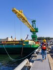 Carlos Murphy, rigger, Code 740, Riggers, helps guide a barge carrying new portal Crane 52 into Pier Bravo at Puget Sound Naval Shipyard & Intermediate Maintenance Facility in Bremerton, Washington. July 14, 2025. (U.S. Navy photo by Wendy Hallmark)