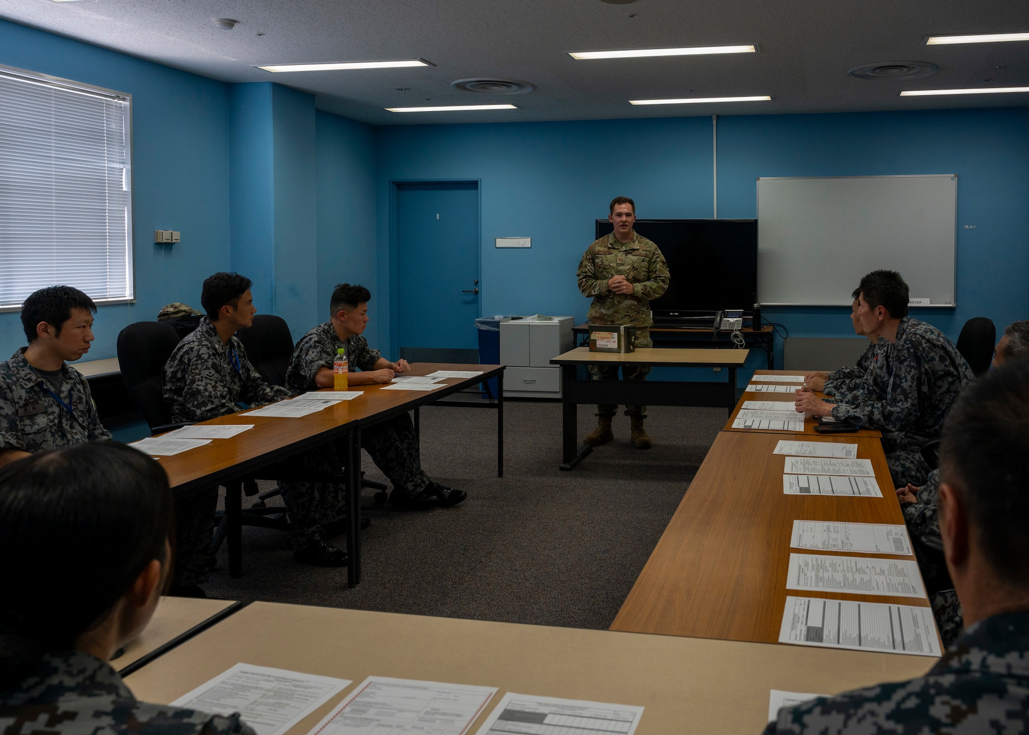 A U.S. Air Force member speaks to Japan Air Self-Defense Force members inside a classroom.