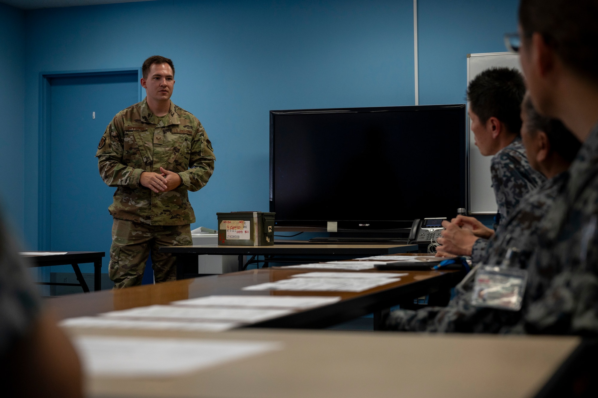 A U.S. Air Force member speaks to Japan Air Self-Defense Force members in a classroom.