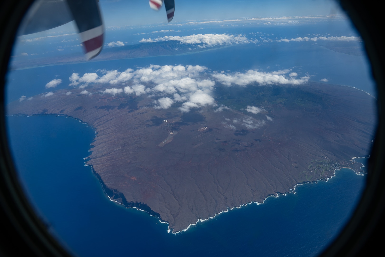 A crew from Coast Guard Air Station Barbers Point flies in an HC-130 Hercules airplane over Lanai, July 30, 2025. The crew conducted an overhead assessment of harbors, waterways and aids to navigation throughout the Hawaiian Islands following the end of a tsunami advisory. (U.S. Coast Guard photo by Petty Officer 3rd Class Avery Tibbets)
