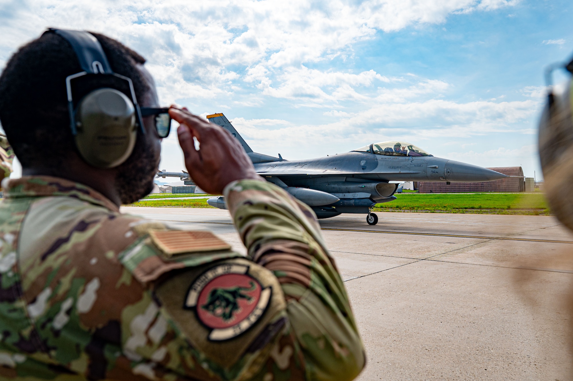 A member of the 35th Maintenance Squadron “Panthers” salutes a 35th Fighter Squadron “Pantons” F-16 Fighting Falcon pilot while it taxis across a runway