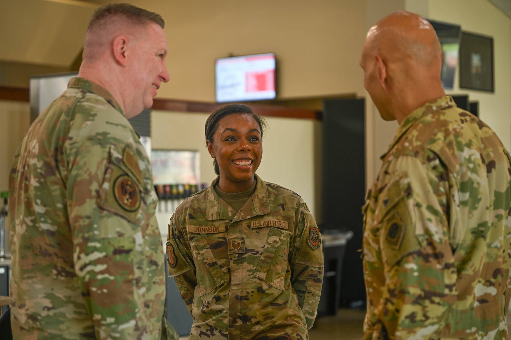 Two men in uniform speak with a woman in uniform.