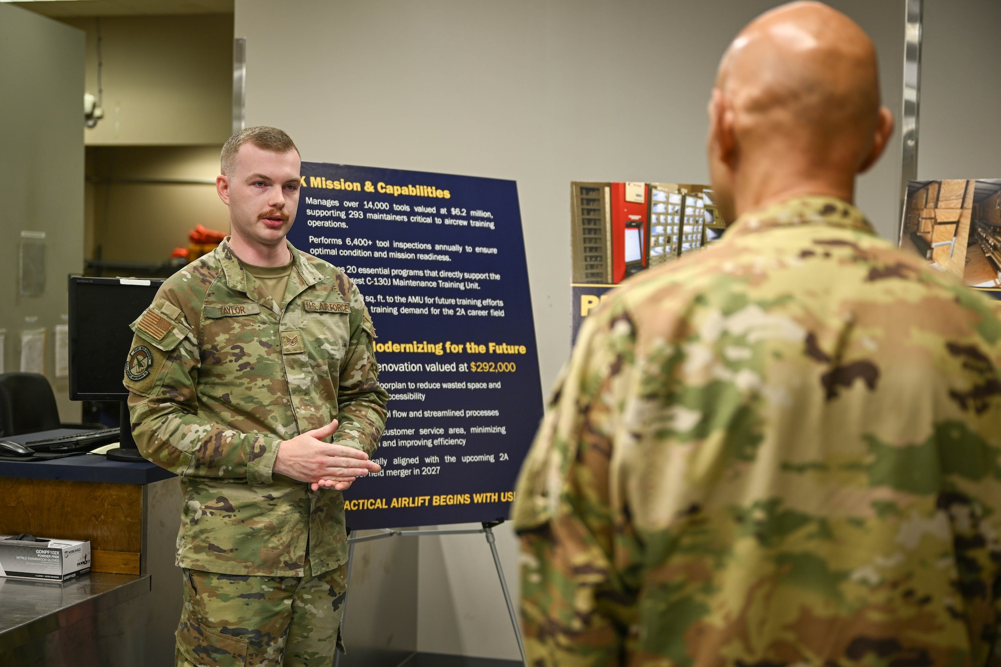 A man in uniform gives a presentation to another man in uniform.