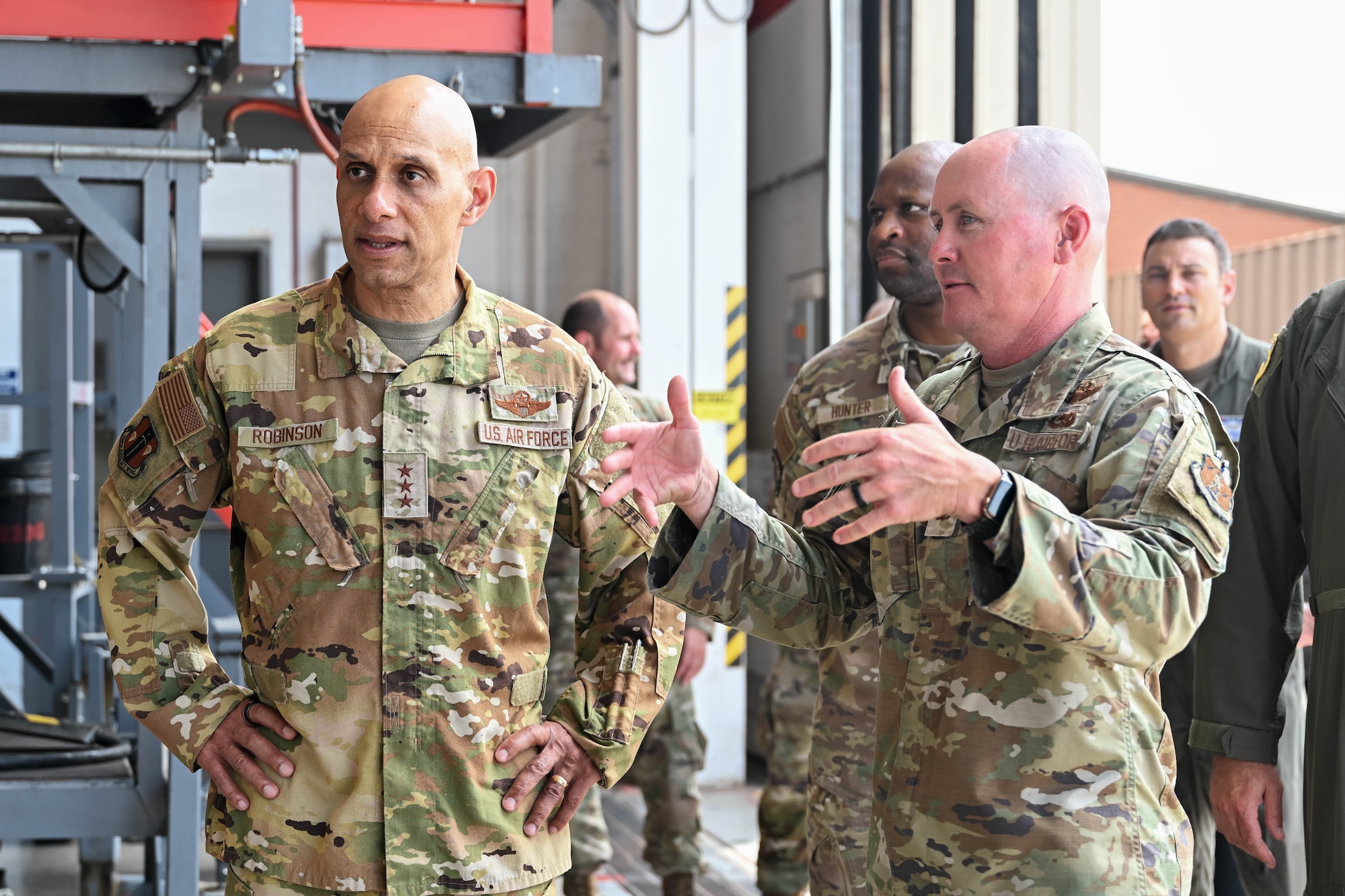 A man in uniform listens to another man in uniform speak.