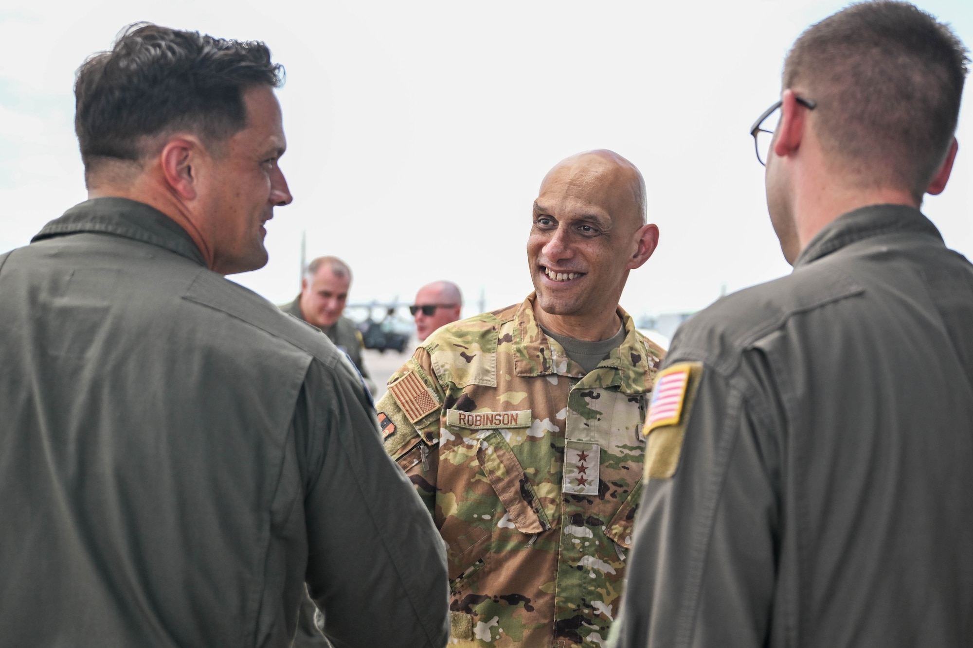 A man in uniform speaks with other men in uniform.