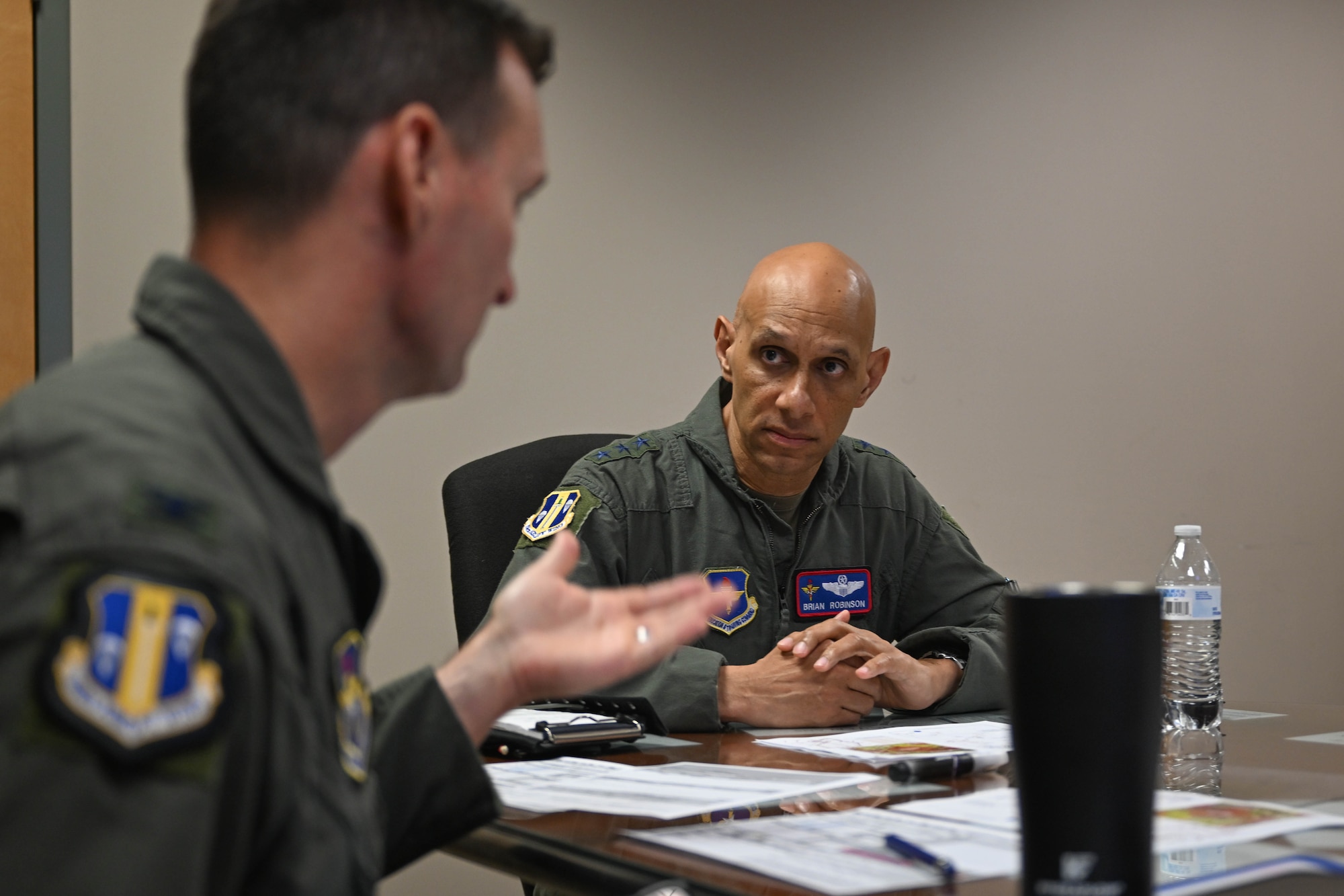 A man in uniform listens to another man in uniform.