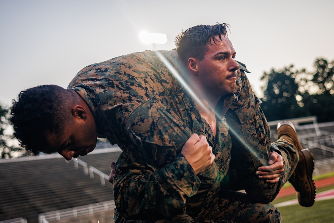 U.S. Marine Corps Lance Cpl. Ethan Wehmeyer, a rifleman with Security Battalion, conducts buddy squats during a Marine Corps Martial Arts Program belt advancement course training exercise at Butler Stadium on Marine Corps Base Quantico, Virginia, July 25, 2025. Marines conduct strenuous exercises as a squad while being randomly pulled to spar to simulate close-quarter combat in stressful situations. (U.S. Marine Corps photo by Lance Cpl. Braydon Rogers)