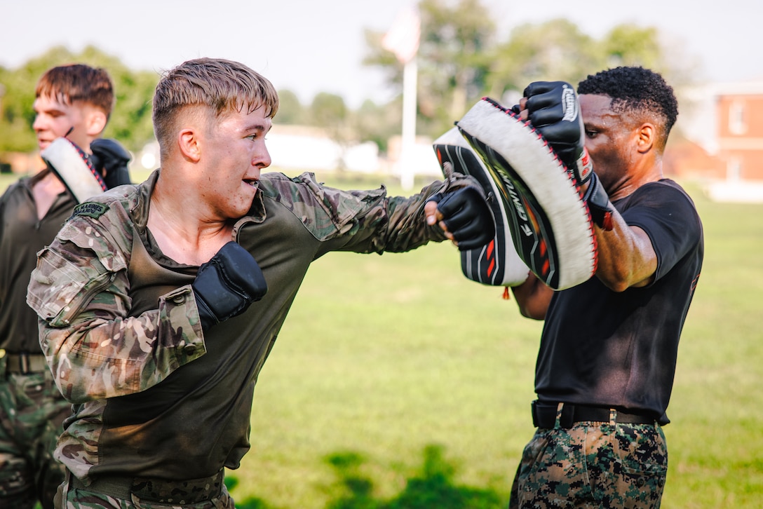 U.S. Marine Corps Staff Sgt. Frankie Cameron III, a martial arts instructor trainer with Training Command, right, and a British Royal Marine conduct hand-to-hand combat techniques during a physical training circuit as part of “Virginia Tempest” at The Basic School on Marine Corps Base Quantico, Virginia, July 30, 2025. Virginia Tempest is an annual training event where Royal Marines and U.S. Marines collaborate in training such as the obstacle course, Marine Corps Martial Arts Program, and other rigorous events, ultimately designed to support interoperability and maintaining the historic working relationship between the organizations. (U.S. Marine Corps photo by Lance Cpl. Braydon Rogers)