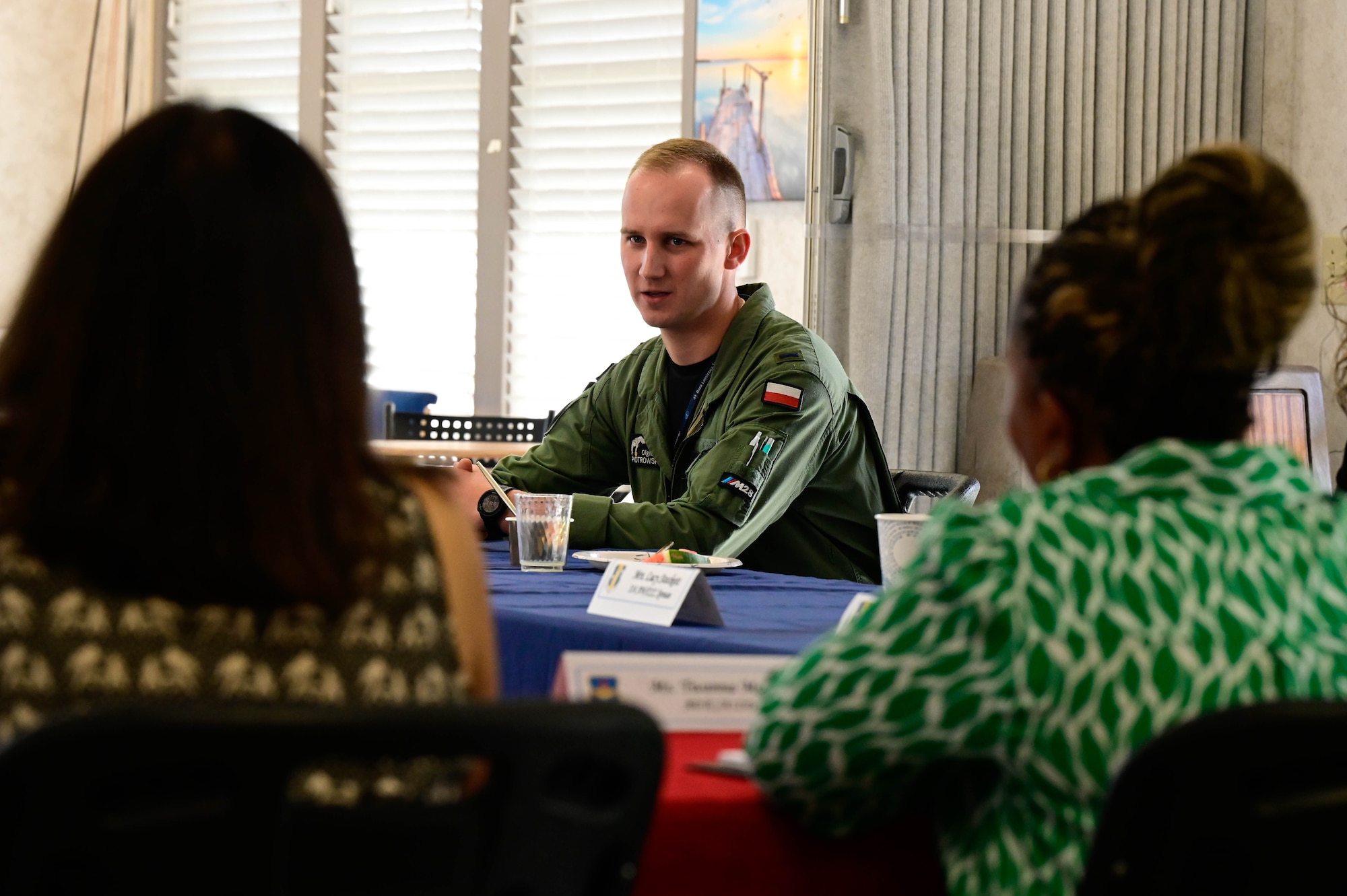 A man in a polish military uniform speaks with two civilian women.