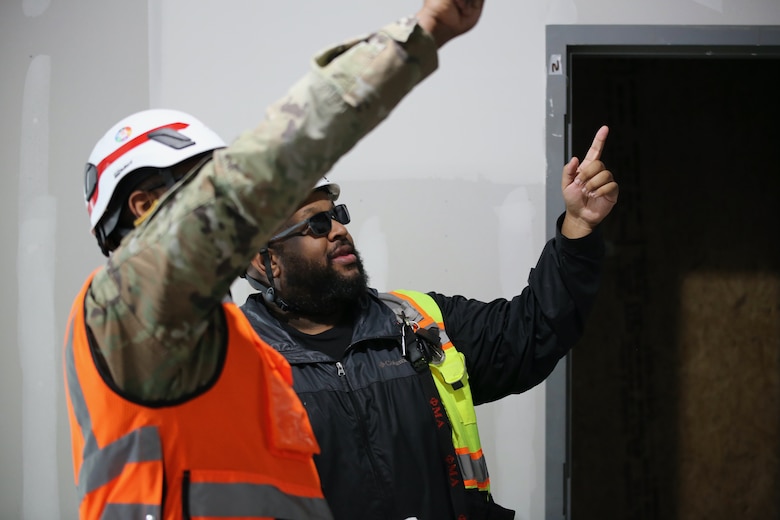 Two men point at building