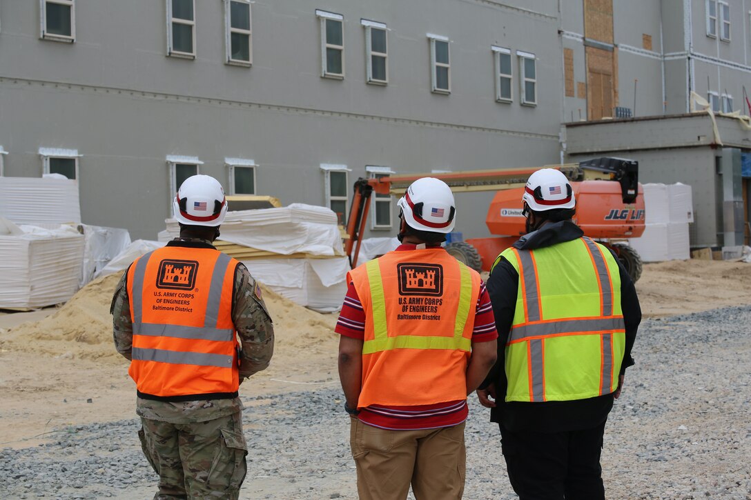 Three men look up at construction project