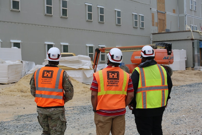 Three men look up at construction project