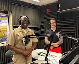 250725-N-MM059-9464 SIGONELLA, Italy. (July 25, 2025). Capt, TaRail Vernon, Director of Naval Hospital (USNH) Sigonella and Hospital Corpsman 3rd Class Brenden Sherrill, assigned to Navy Medical Readiness Training Command (NMRTC) Sigonella, prepare for Armed Forces Network (AFN) Patient Informational Minute radio segment focused on emergency care services. The segment highlighted the hospital’s 24/7 services, which is staffed by physicians, trauma-trained nurses, and EMT-certified Corpsmen who provide immediate care, triage, and coordination for life-threatening medical situations. (U.S. Navy photo by Lieutenant Junior Grade Gabriela Santesteban)