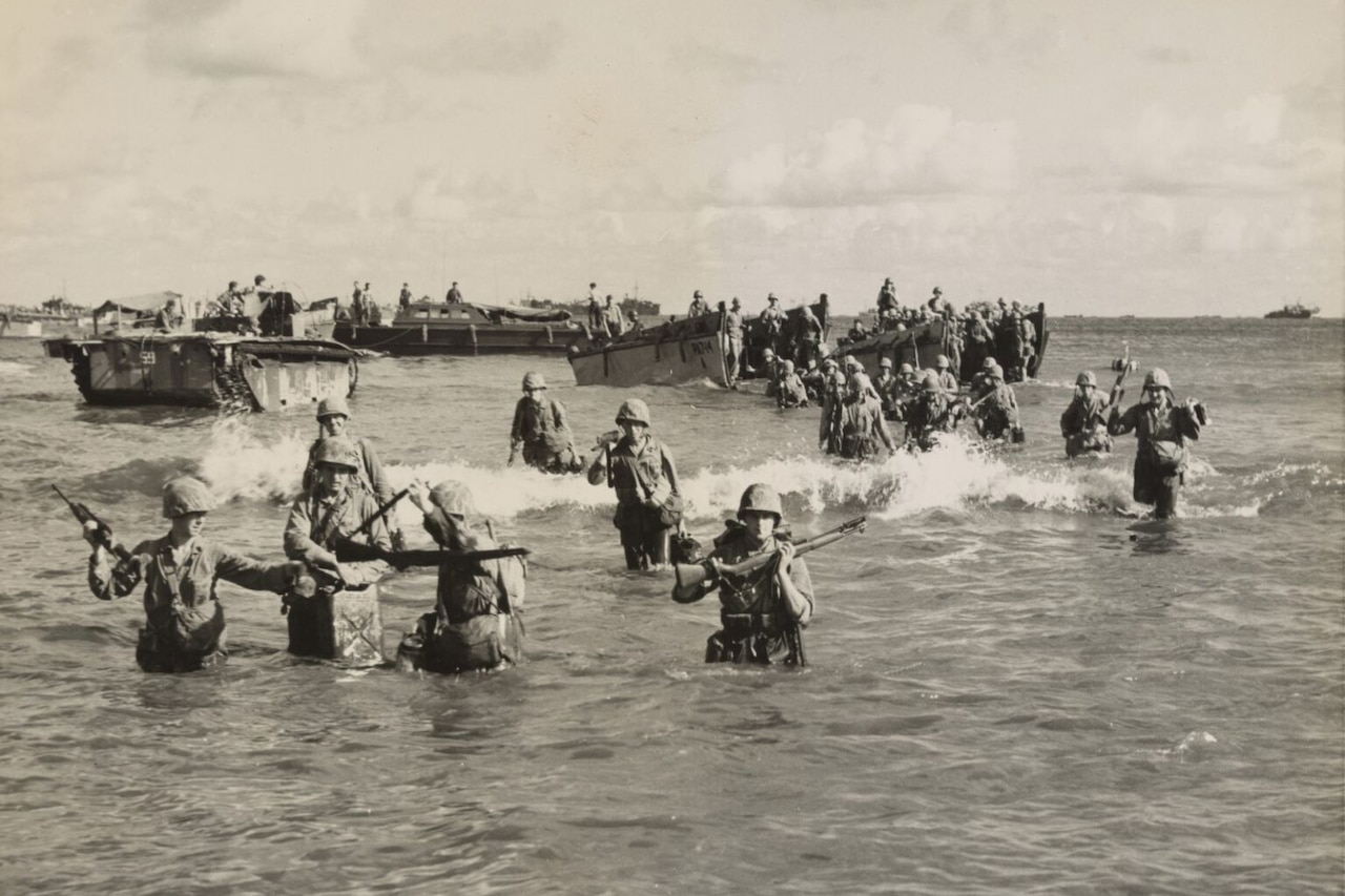 Several men getting off small boats wade through waist-deep water toward shore.