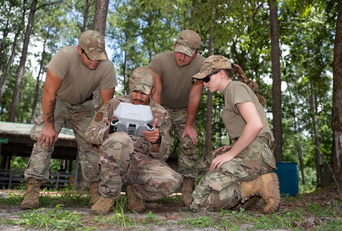 Four people look at a drone screen.