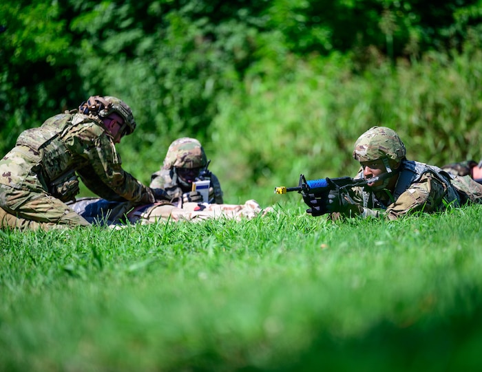 Service members perform care while another guards.