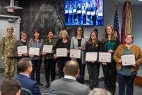 Col. Michelle M. Williams, U.S. Army Financial Management Command commander, presents the USAFMCOM Army Accounting and Audit Operations Fund Balance with Treasury team with certificates of appreciation from Christine Wormuth, Secretary of the Army, in recognition of their efforts to downgrade FBwT as a material weakness in the Army’s General Fund audit  during a town hall at the Maj. Gen. Emmett J. Bean Federal Center in Indianapolis Feb. 12, 2025. Pictured next to Williams, from left to right, are LuAnn Watson, Shannon Tabbert, Esther Richard, Cindy Price, Karen Percinel, Amanda McCoy, Denise Gallion, and Makayla Chriss. (U.S. Army photo by Mark R. W. Orders-Woempner)