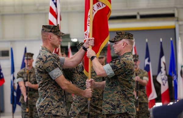 Col. Kirk M. Spangenberg, right, outgoing commander of Marine Depot Maintenance Command (MDMC), passes the unit colors to Col. Nicolas J. Lozar, left, during a change of command ceremony at MDMC’s Production Plant Albany on Marine Corps Logistics Base Albany, Georgia, July 31. Master Sgt. Travis Aaron Thomas, MDMC’s senior enlisted advisor, salutes as the colors are passed.
