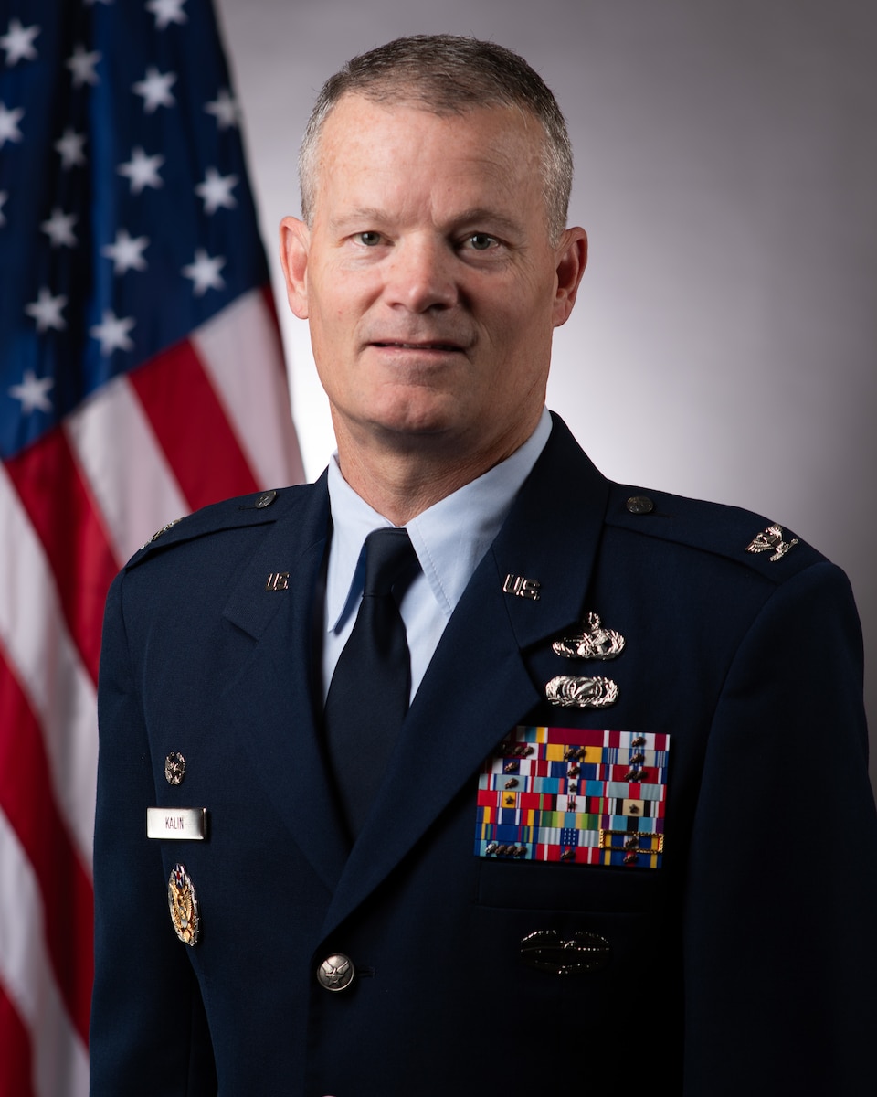 A man in a uniform in front of a US flag