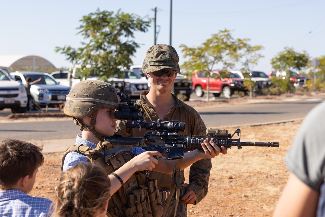 U.S. Marine Corps Lance Cpl. Logan S. Folta, a grenadier with 2nd Battalion, 1st Marine Regiment, Marine Rotational Force – Darwin 25.3, presents an M27 infantry automatic rifle to local youth during a family event in Cloncurry, Queensland, Australia, July 24, 2025. MRF-D 25.3 is an annual six-month rotational deployment to enhance interoperability with the Australian Defence Force and provide a forward postured crisis response force in the Indo-Pacific. Folta is a native of Vermont. (U.S. Marine Corps photo by Sgt. Ezekieljay Correa)