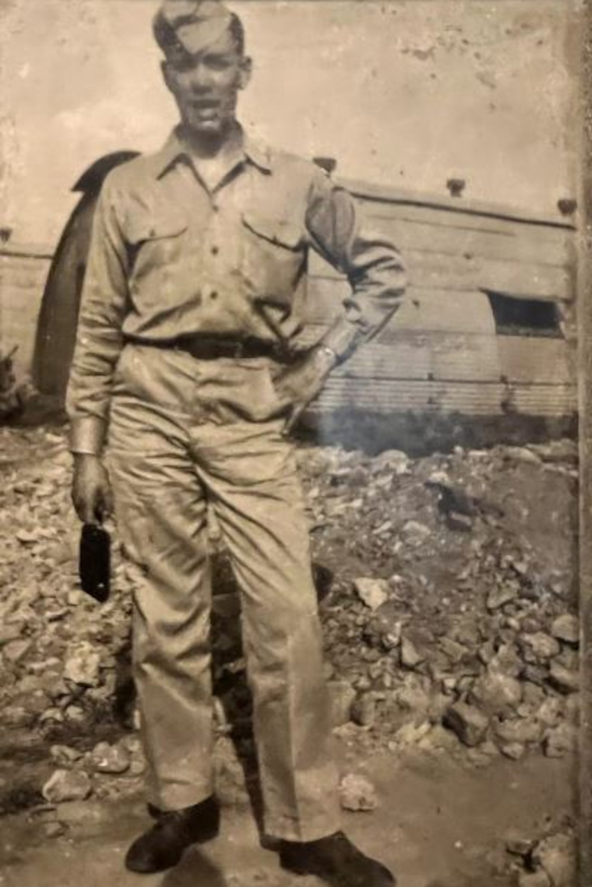 A man in military attire poses in a black and white photograph.
