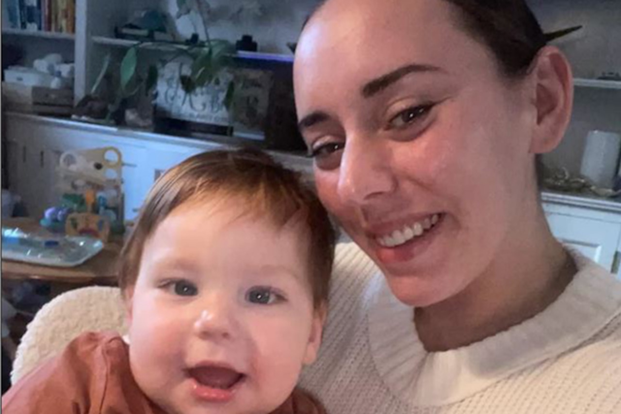 A woman poses for a photo with a toddler.