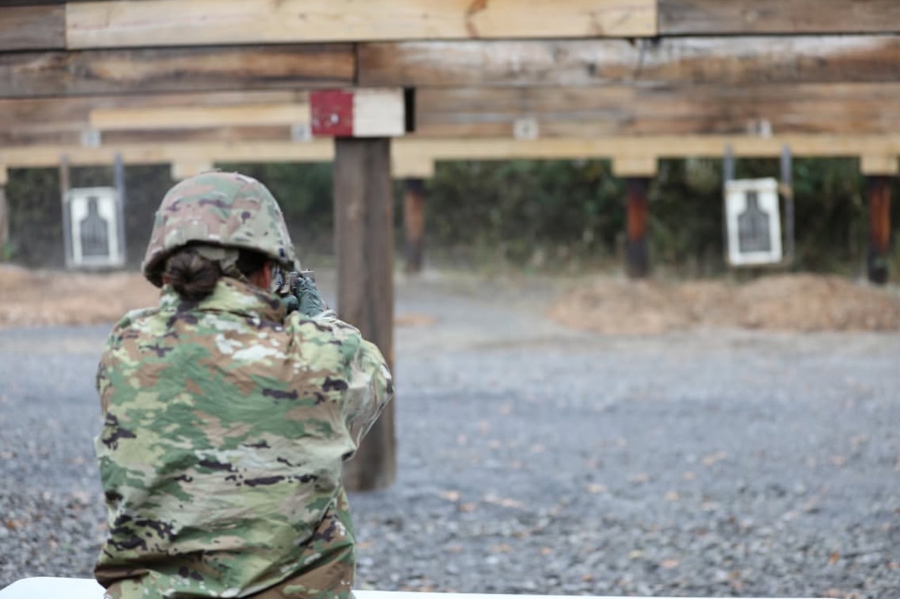 A service member fires a pistol at a target.