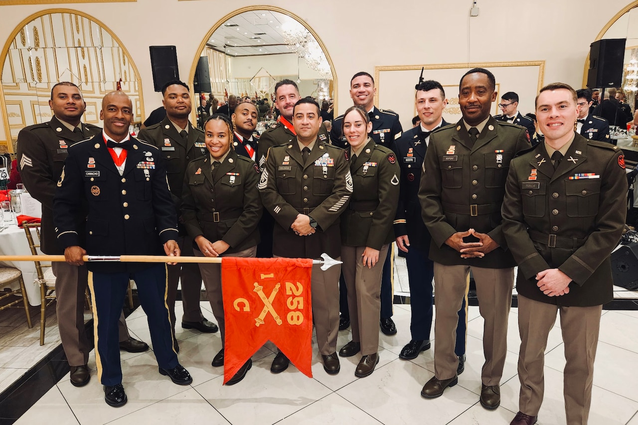A group of people in military attire pose for a photo indoors.