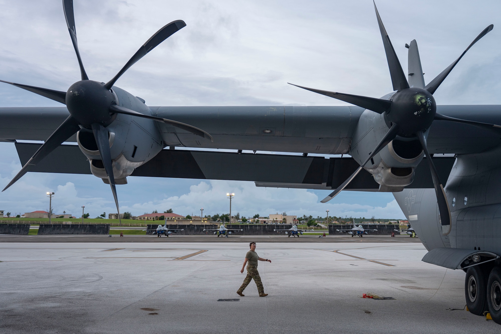 A pilot walks under the wing of an aircraft.
