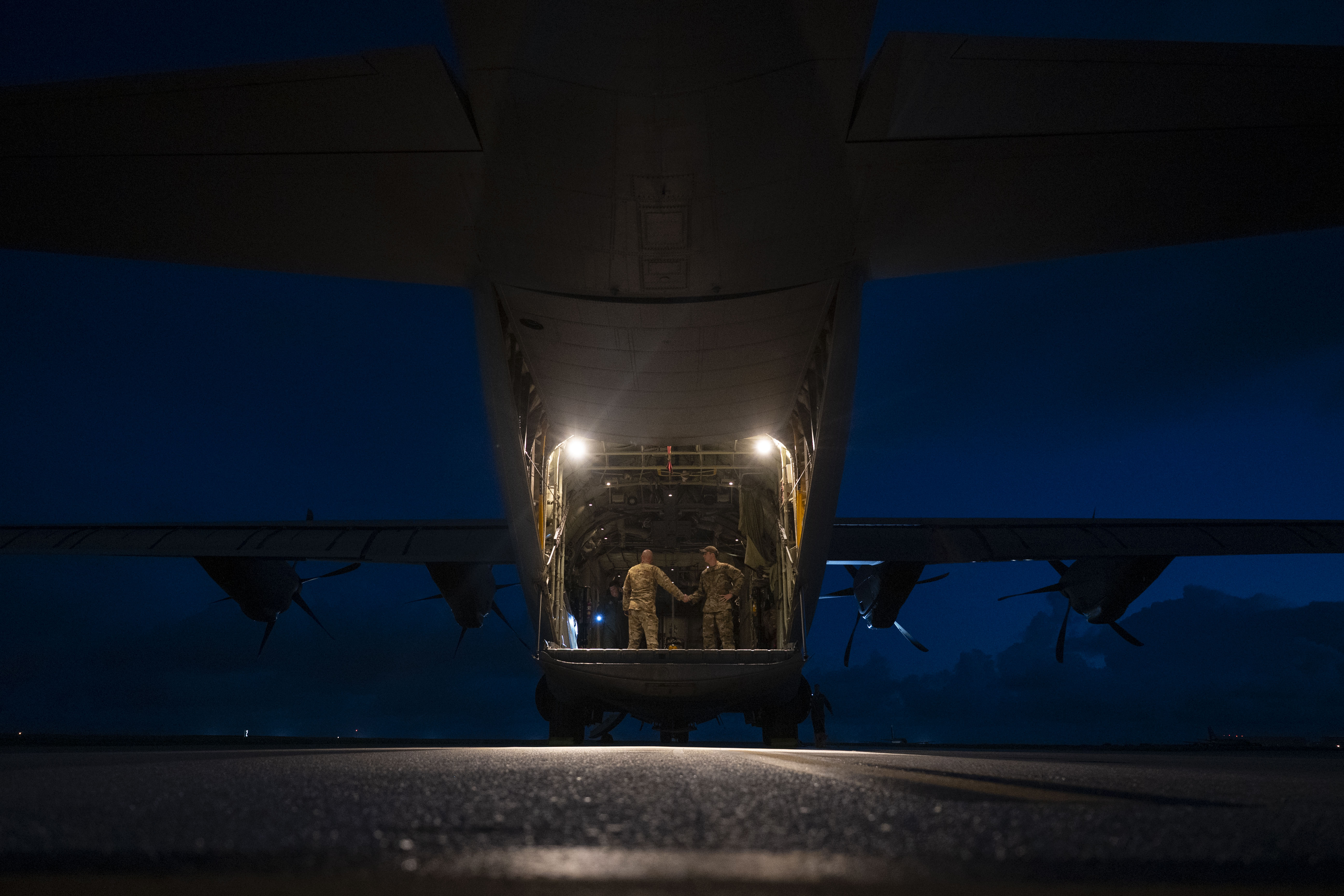Aircrew conduct pre-flight checks at the back of an aircraft.