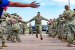 Space Force Spc. 4 Nikolaos Garske receives congratulations while running through a ceremonial gauntlet after being selected for promotion to sergeant during a guardian promotion ceremony at Schriever Space Force Base, Colorado, July 25, 2025.
