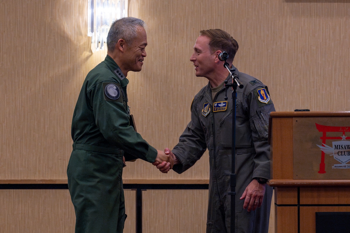 U.S. Air Force Col. Paul Davidson, right, 35th Fighter Wing commander, shakes hands with Japan Air Self-Defense Force (JASDF) Lt. Gen. Hiroshi Kameoka, Northern Air Defense Force commander, during an all-call at Misawa Air Base, Japan, May 23, 2025.