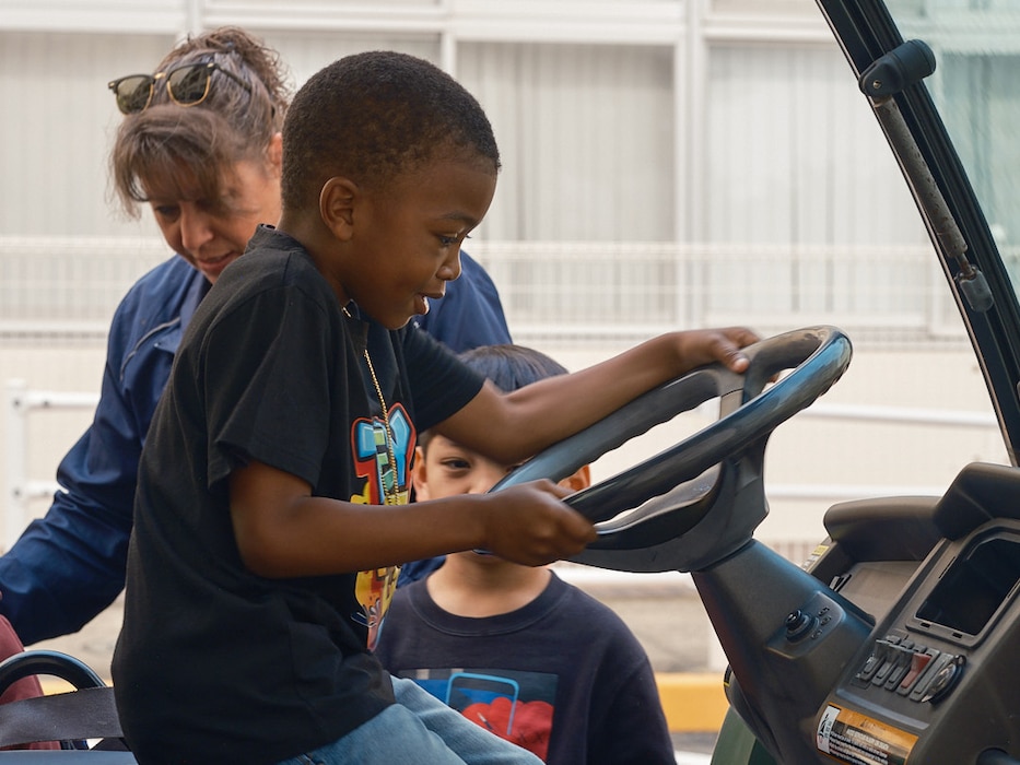 A young boy from Yokosuka Primary School pretends to drive a tractor from the driver's seat of the vehicle at CAReer Day
