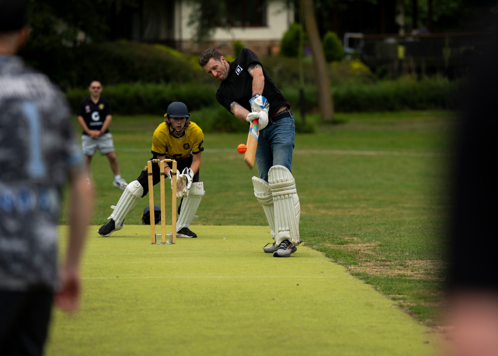 U.S. Air Force Col. Ryan Garlow, right, 100th Air Refueling Wing commander, strikes a cricket ball during a pick-up game at Mildenhall Cricket Club, Mildenhall, England, May 30, 2025. Children and parents in the local area surrounding RAF Mildenhall and RAF Lakenheath taught U.S. service members how to play cricket. (U.S. Air Force photo by Staff Sgt. Nash Truitt)