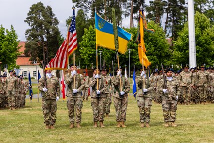 The color guard stands during the Joint Multinational Training Group-Ukraine transfer of authority ceremony with the 278th Armored Cavalry Regiment colors uncased at the Joint Multinational Training Group-Ukraine transfer of authority ceremony at Tower Barracks, Grafenwoehr, Germany, June 1, 2025.