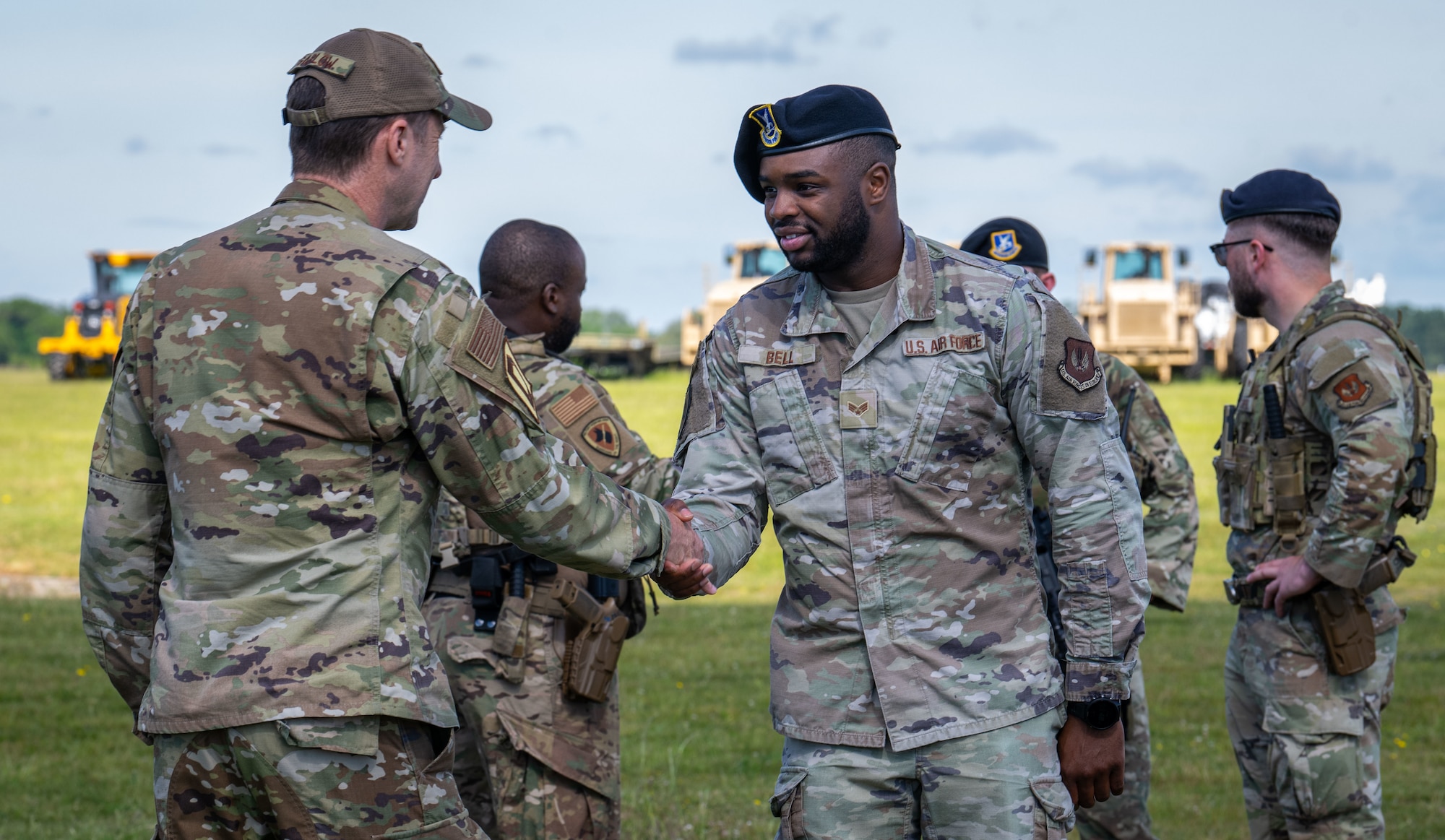 U.S. Air Force Col. Ryan Garlow, left, 100th Air Refueling Wing commander, coins Senior Airman Jelani Bell, 100th Security Forces Squadron military working dog handler, after a Day in the Life integration with the 100th SFS at RAF Mildenhall, England, May 30, 2025.
