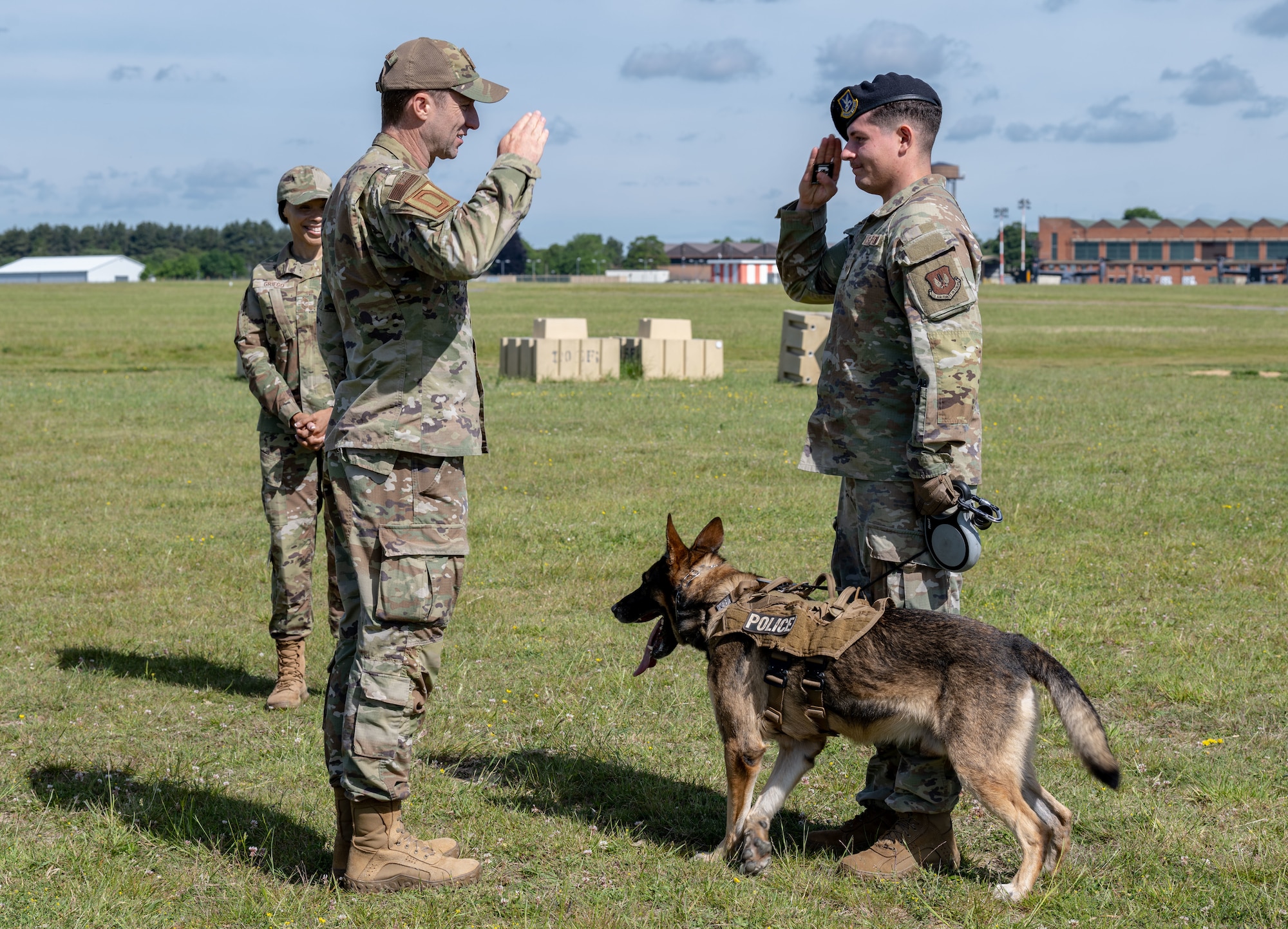 U.S. Air Force Senior Airman Samuel Mcpheron, right, 100th Security Forces Squadron military working dog handler, renders a salute to Col. Ryan Garlow, 100th Air Refueling Wing commander, after being coined during a Day in the Life integration with the 100th SFS at RAF Mildenhall, England, May 30, 2025.