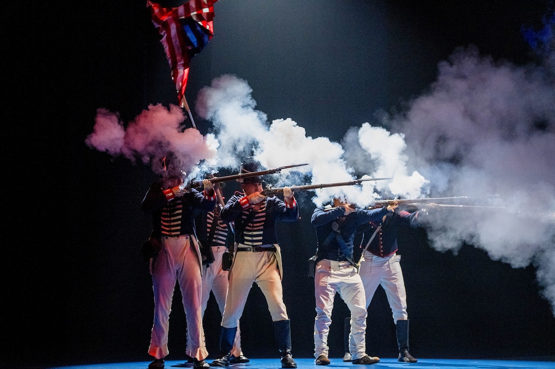 Five soldiers dressed in period uniforms fire weapons, creating clouds of smoke in a dark room.