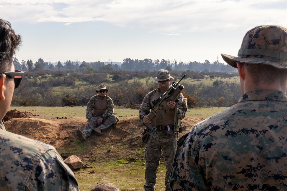 U.S. Marines gather for a class led by Chilean marines on their weapons systems and how they operate them during a break from a live fire exercise taking place during Southern Star 25, at Fuerte Aguayo, Chile, May 29, 2025. Southern Star is a multinational training exercise emphasizing operational and tactical missions, bringing together joint, combined, interagency, and military forces to strengthen coordination and interoperability within a unified special operations command. (U.S. Marine Corps photo by Lance Cpl. Payton Goodrich)