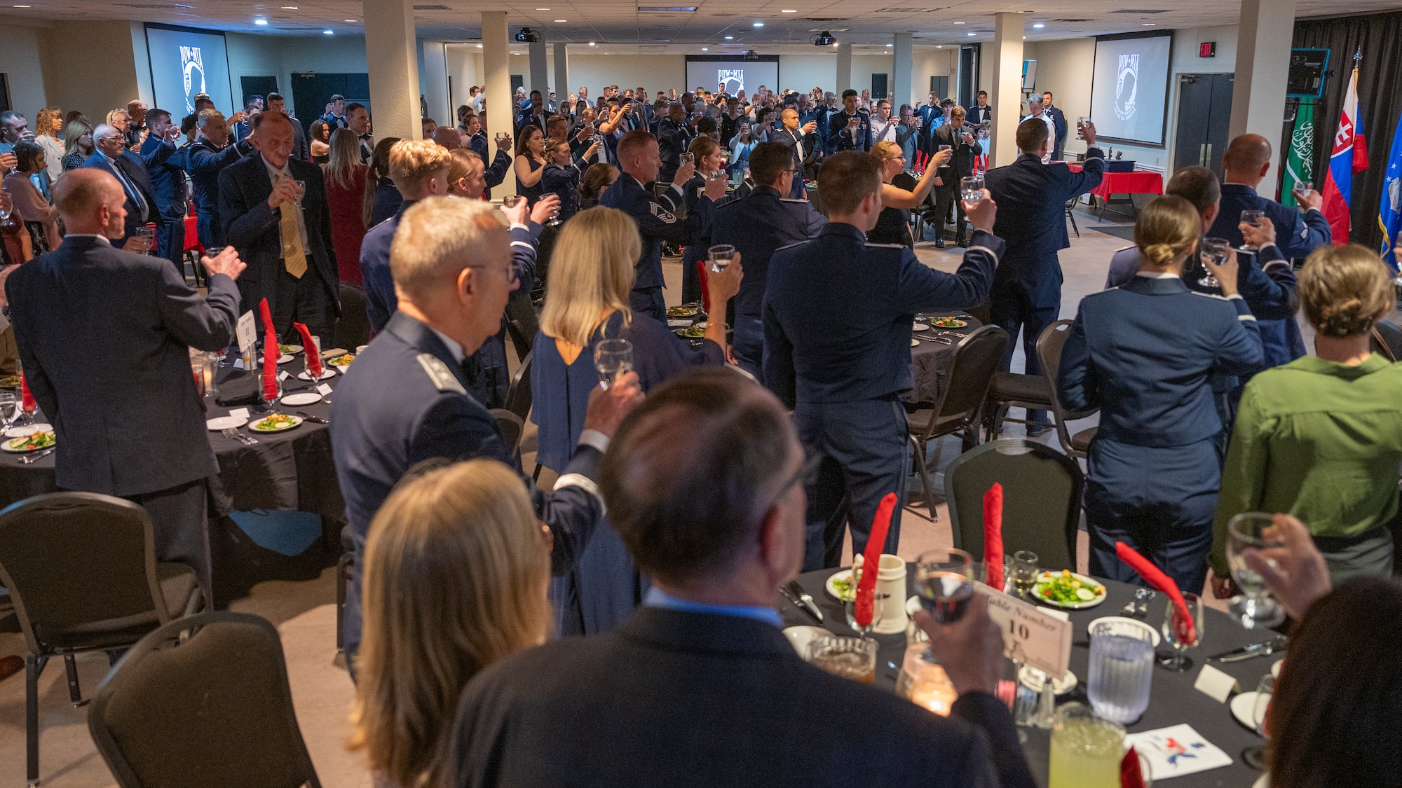 Attendees at the UPT Class 25-10 Graduation raise their glasses in salute to fallen pilots at Laughlin Air Force Base, Texas, May 29, 2025. The salute originated from Navy Capt. Jerry Coffee while he was in a Vietnamese prison cell, where he noticed a formation of four F-105s during a bombing run. The lead aircraft was trailing smoke and the rest of the flight pulled away, leaving the damaged aircraft alone. After it had passed and presuming the worst, he wrote a toast to the unfortunate pilot and all those who had gone before him. (U.S. Air Force photo by Staff Sgt. Nicholas Larsen)