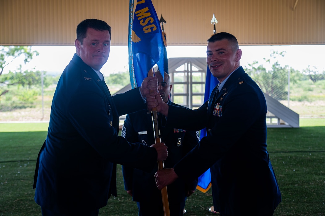 U.S. Air Force Col. Timothy Dalby, 17th Mission Support Group commander, presents Maj. Jonathan Estep, incoming 17th Security Forces Squadron commander, , incoming 17th Security Forces Squadron commander, with the guidon during the change of command ceremony at the Military Working Dogs kennels’ overhang, Goodfellow Air Force Base, Texas, June 2, 2025. The 17th SFS’s mission is to protect, defend, and fight by delivering world-class Air Base Ground Defense and enabling full-spectrum combat operations. (U.S. Air Force photo by Airman 1st Class James Salellas)