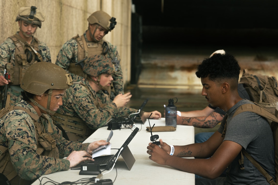 U.S. Marines with Combat Logistics Battalion 26, 22nd Marine Expeditionary Unit, process U.S. citizens during a simulated non-combatant evacuation operation, as part of Iwo Jima Amphibious Ready Group Marine Expeditionary Unit exercise, at Marine Corps Base Stone Bay, North Carolina, May 28, 2025. During ARGMEUEX, the 22nd MEU, aboard IWOARG shipping, conducts various mission essential tasks that enhance operational readiness and lethality as a unified IWOARG/22 MEU team. (U.S. Marine Corps photo by Cpl. Maurion Moore)