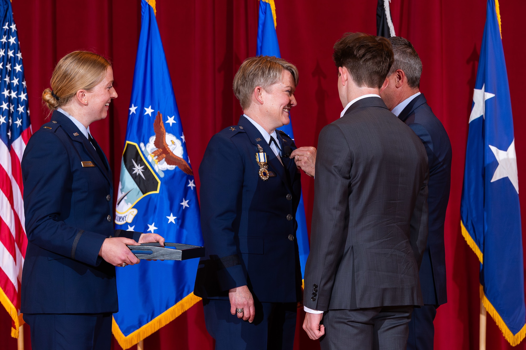 A photo of Brig. Gen. Linell Letendre receiving a retirement pin from her husband while her children watch