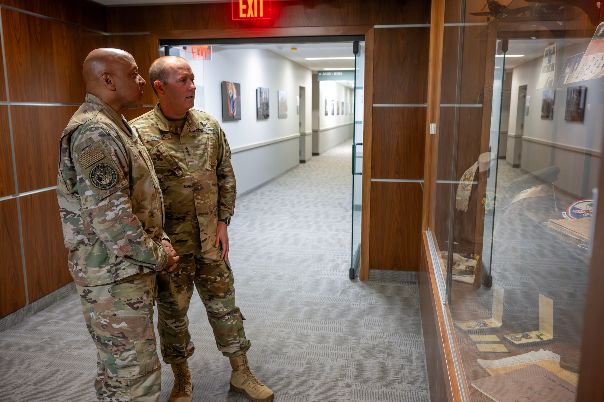 Two senior military members view a display case.