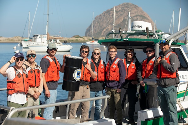 People on boat hold barrel-shaped device