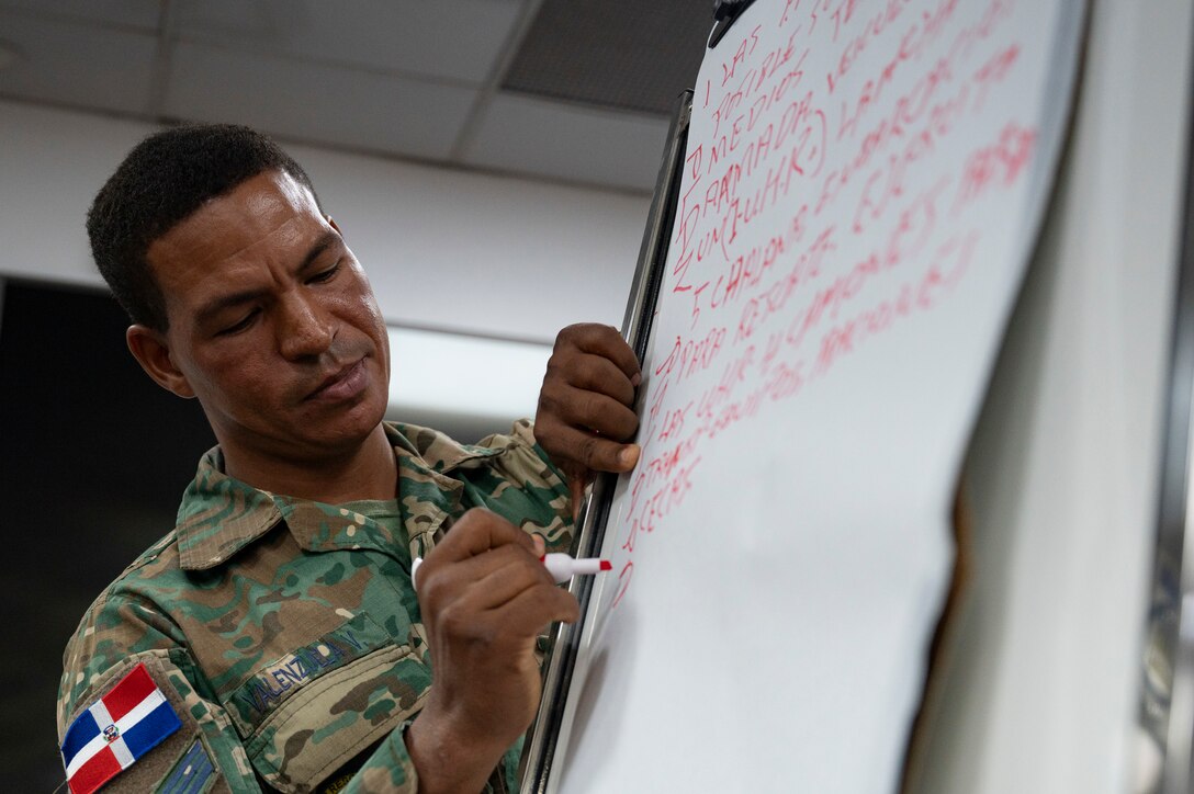 Dominican Republic Air Force Sgt. Bienuendo Valencia, COE liaison, writes down on the leader action board during a Jaguar Sentinel knowledge exchange in Santo Domingo, Dominican Republic, May 8, 2025. The scenario was given to three groups that included U.S. and Dominican Republic service members, policemen and emergency management personnel, who responded with a unified approach to answer the various injects. (U.S. Air Force photo by Staff Sgt. Sadie Colbert)