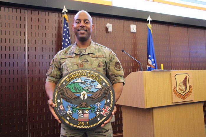 U.S. Airman stands holding a Bamboo Eagle Emblem