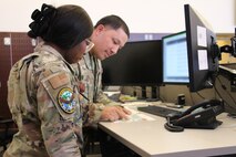 uniformed U.S. Airmen work on computers