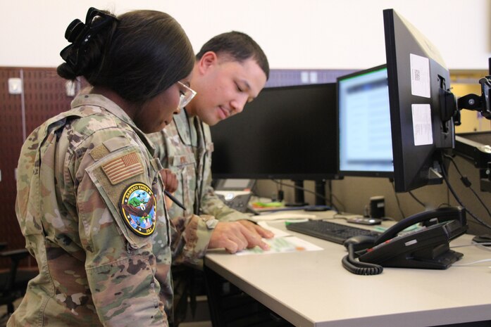 uniformed U.S. Airmen work on computers