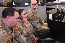 uniformed U.S. Airmen work on computers